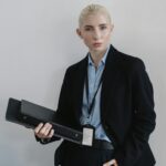 Confident businesswoman in formal attire holding a black folder indoors.